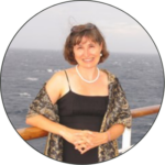 Image of Heather Blenkiron wearing a lovely evening dress onboard a Galapagos cruise ship. She is standing by the railing, beaming with joy.