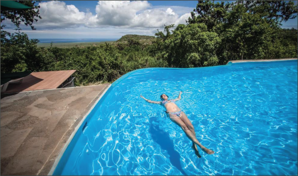 A woman lounges in the water of a swimming pool at the Safari Lodge on a beautiful sunny day.