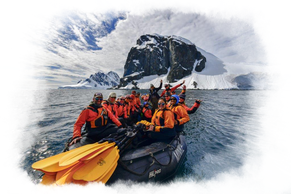 A group of people wearing orange life jackets in a zodiac boat wave.