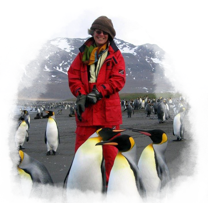 A woman in a red coat and snow pants smiles behind three king penguins.